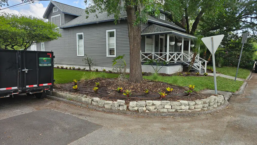 A Woods company trailer beside a new stone-edged corner planting bed with crotons