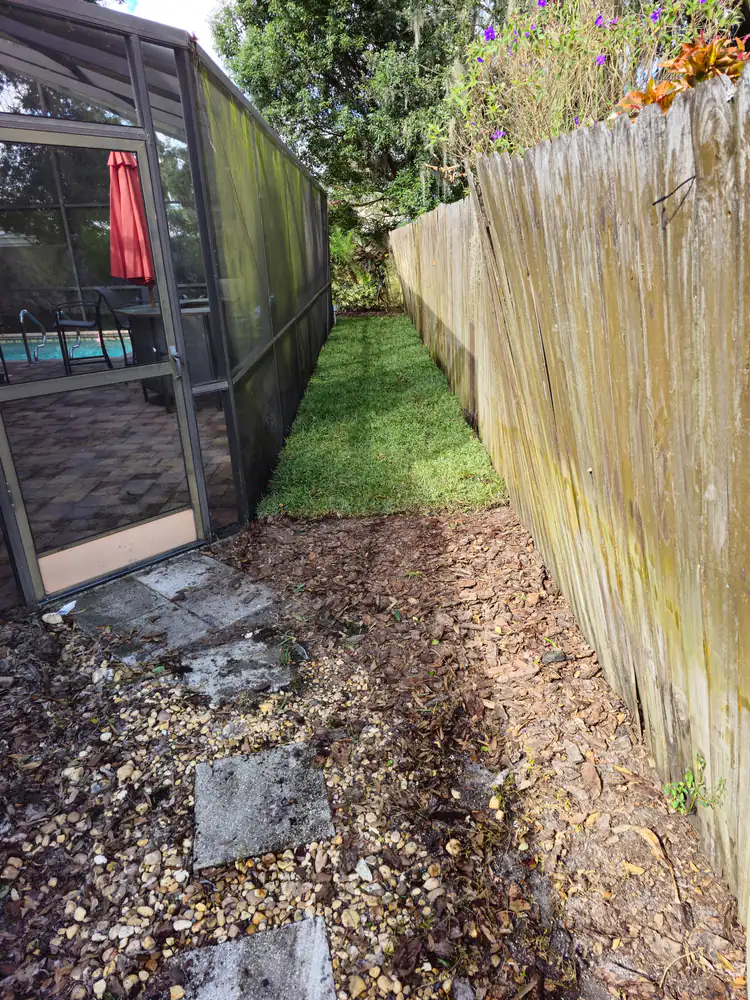 Freshly laid sod pieces in a narrow side yard along a wooden fence