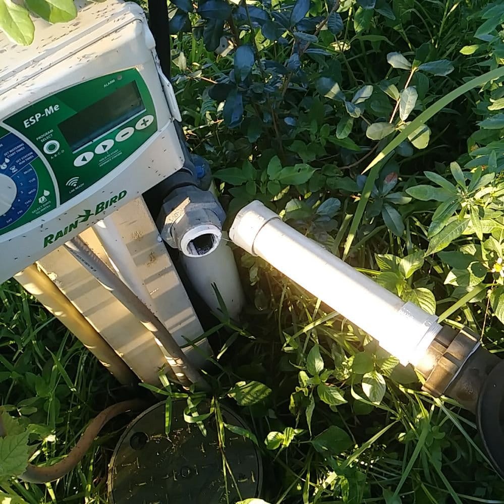 Rain Bird ESP-Me irrigation controller beside an open mainline pipe